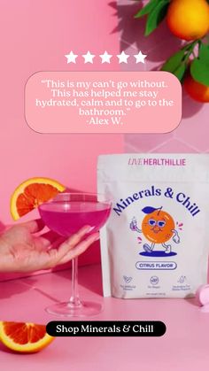 a person holding a pink cocktail in front of some oranges and an ad for minerals & chilli