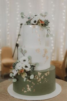 a white and green wedding cake with flowers on top