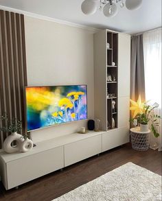 a living room with a large flat screen tv mounted on the wall next to a white rug