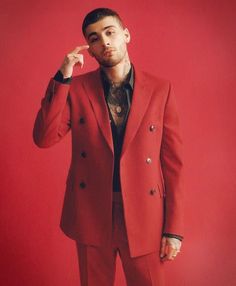 a man in a red suit posing for the camera with his hand on his chin