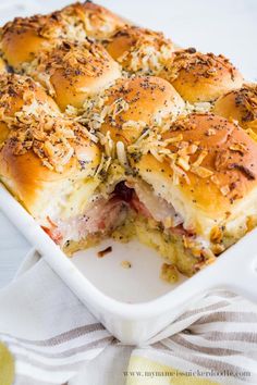 a white casserole dish filled with ham and cheese sliders on top of a towel