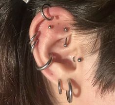 a woman with three different piercings on her ear and behind the ear is a pair of scissors