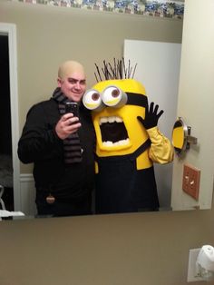 a man taking a selfie in front of a mirror next to a minion