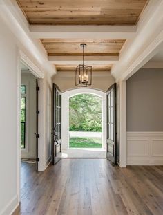 an open door leading into a large room with wood flooring and white trim on the walls