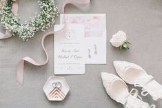 the wedding stationery is laid out with shoes and flowers