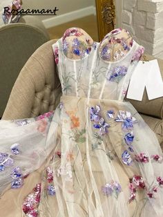 a dress with flowers on it sitting on a chair