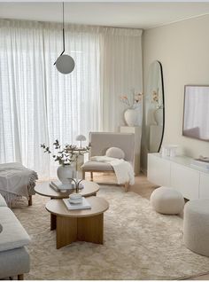 a living room filled with lots of furniture and white curtains on the window sill