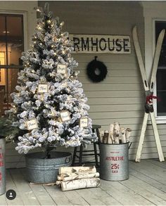 a white christmas tree sitting on top of a wooden floor next to two buckets