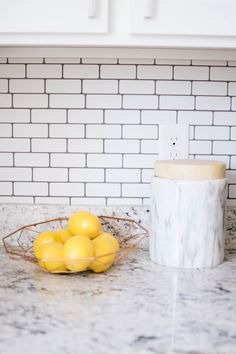 some lemons are in a bowl on the counter