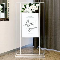 there is a sign that has been placed on the floor next to a vase with flowers in it