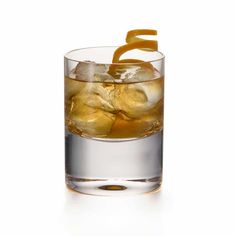 a glass filled with ice and an orange peel on the rim, sitting on a white surface