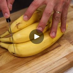 a person cutting bananas with a knife on a wooden board