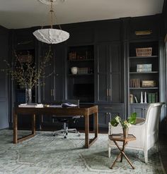 an office with black cabinets and a desk in the middle is decorated with greenery