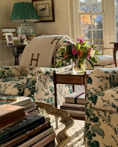 a living room filled with lots of furniture and flowers on top of a coffee table