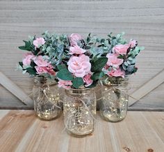 three vases with pink flowers and greenery in them