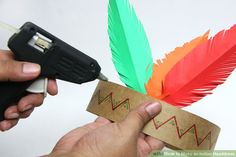 a person is using a small device to make a paper feather headband with scissors