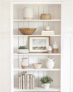 a white bookcase filled with books and vases