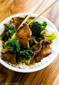 beef and broccoli on rice in a bowl with chopsticks