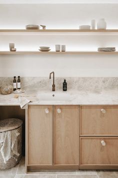 a kitchen with wooden cabinets and white marble counter tops, along with plates on the shelves