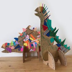 two cardboard dinosaurs made to look like they are standing next to each other on a wooden table