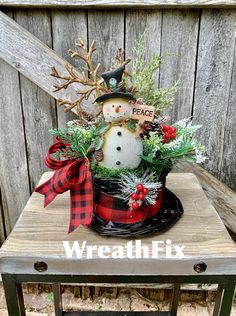 a snowman in a hat with evergreens and pine cones is sitting on top of a table