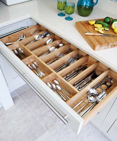 an organized drawer with utensils and spoons in the drawers, on a kitchen countertop