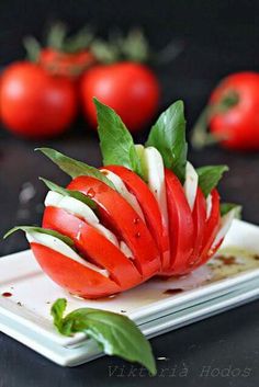 a white plate topped with sliced tomatoes and green leaves