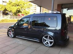 a black van parked in front of a building with white rims and chrome wheels