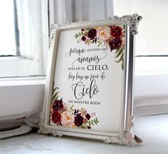 a framed sign with flowers on it sitting next to a window sill in front of a window