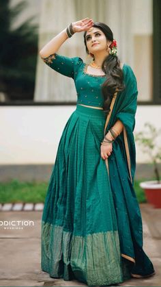 a woman in a green dress posing for the camera with her hand on her head