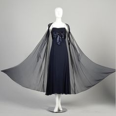 "You'll look like a princess in this elegant 1960s navy blue silk evening gown by Cameo Evening Fashions. This formal dress is sleeveless, has an empire waist, and features a large silk bow on the bodice. Its accompanying translucent, long floating vest makes this gorgeous dress flowy and feminine. Condition: Very Good Condition Details:  Vest: No notable flaws Dress: Lining has a lightened spot at the center front hem, not visible when worn. Size Marked: Unmarked Approximate Size: Small **Please Check Measurements to be Sure! Textile: Unmarked Silk Lining Type: Vest: Unlined, Dress: Fully Lined Closure: Vest: Center Front Hook, Dress: Metal Back Zip, and Hooks Label: Cameo Evening Fashions Era: 1960s Measurements-  Vest: Shoulder to Shoulder: 17\" Chest/Bust: 46\" Waist: 54\" Hips: 68\" L Silk Evening Gown, Formal Evening Gown, Chiffon Evening Dresses, Blue Sheers, Dress Flowy, Empire Waistline, Dress Navy Blue, Evening Gowns Formal, Navy Blue Dresses