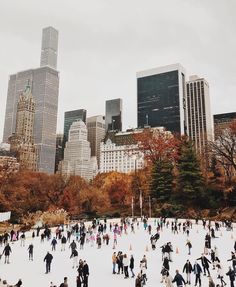 many people are skating on an ice rink in the middle of a city with tall buildings