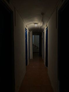 an empty hallway with blue shutters leading into the light at the end of the room