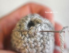 someone is holding a yarn ball with two needles in the middle and another thread on the other end