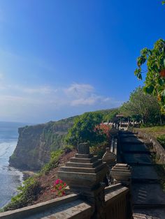 the walkway to the beach is lined with flowers and greenery, along with an ocean view