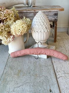 a vase with flowers sitting on top of a table next to an egg shaped object