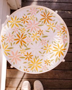 a plate with flowers painted on it hanging from a hook in front of someone's feet