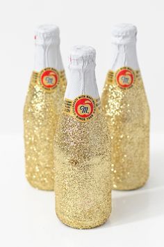 three gold glitter bottles are sitting next to each other