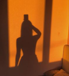 the shadow of a man in a top hat on a wall next to a bed