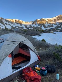 a tent is set up on the ground with mountains in the background