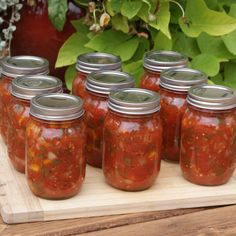 six jars of canned salsa sit on a cutting board