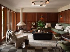 a living room filled with lots of furniture next to a window covered in wooden paneling