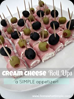 small desserts are arranged on sticks with black and green apples in the middle, sitting on a white tablecloth