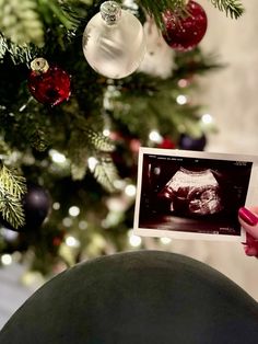 someone holding up an old photo in front of a christmas tree