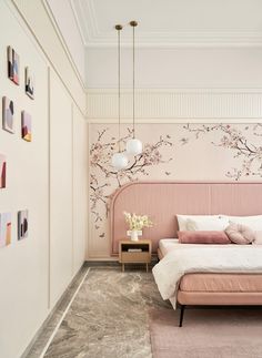 a bedroom with a pink bed and floral wallpaper, along with pictures on the walls