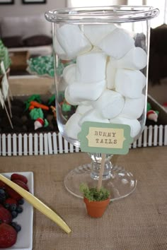 there is a glass with marshmallows in it and some strawberries on the table