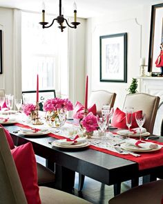 a dining room table set with place settings and pink flowers on the centerpieces