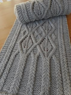 a gray knitted blanket sitting on top of a wooden floor