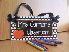 a teacher's classroom sign with crayons and markers on the table next to it