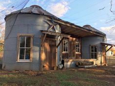 an old blue house with a round metal structure on the front and side of it